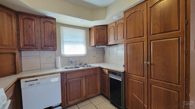 kitchen with a sink, tasteful backsplash, light countertops, and dishwasher