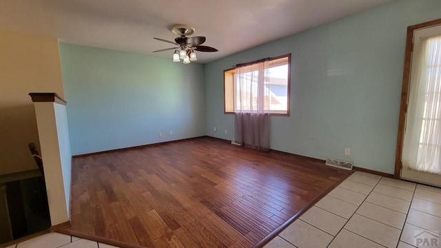 empty room featuring a ceiling fan, light wood-type flooring, visible vents, and baseboards