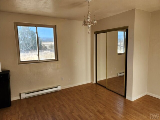 7787 State Highway 78, Beulah, CO 81023 - unfurnished bedroom with a baseboard radiator, wood finished floors, a chandelier, and multiple windows