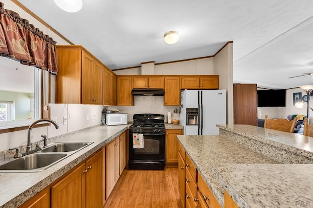 181 6th St, Penrose, CO 81240 - kitchen featuring white appliances, a sink, vaulted ceiling, under cabinet range hood, and brown cabinets