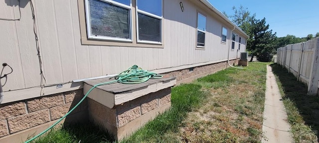 view of side of home featuring central AC unit, crawl space, and fence