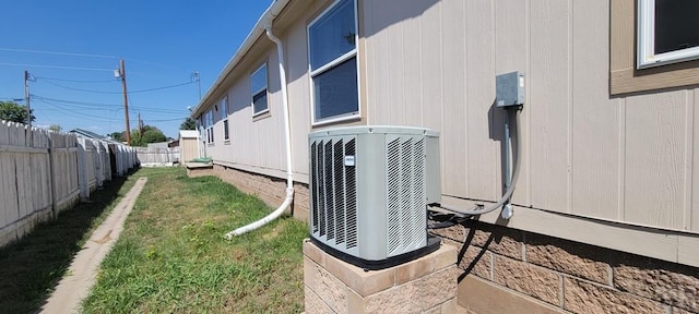 exterior space with fence, a lawn, and central AC unit