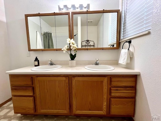 full bath featuring double vanity, visible vents, and a sink