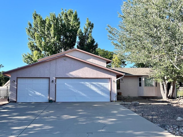 single story home featuring an attached garage, concrete driveway, and stucco siding