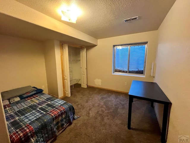 carpeted bedroom featuring a textured ceiling, a closet, visible vents, and baseboards