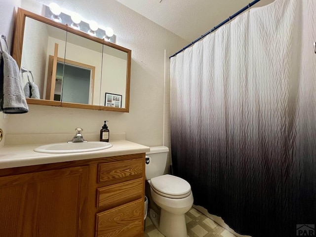 full bathroom featuring toilet, a textured wall, a shower with shower curtain, and vanity