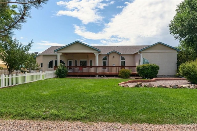 view of front of property with fence, a deck, a front lawn, and stucco siding