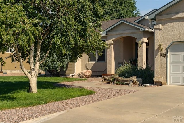 view of front of house featuring a garage, a front lawn, concrete driveway, and stucco siding