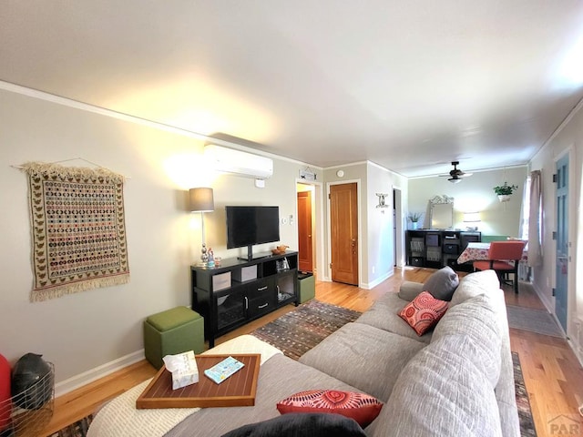 living room featuring baseboards, a wall mounted air conditioner, light wood-style floors, and ornamental molding