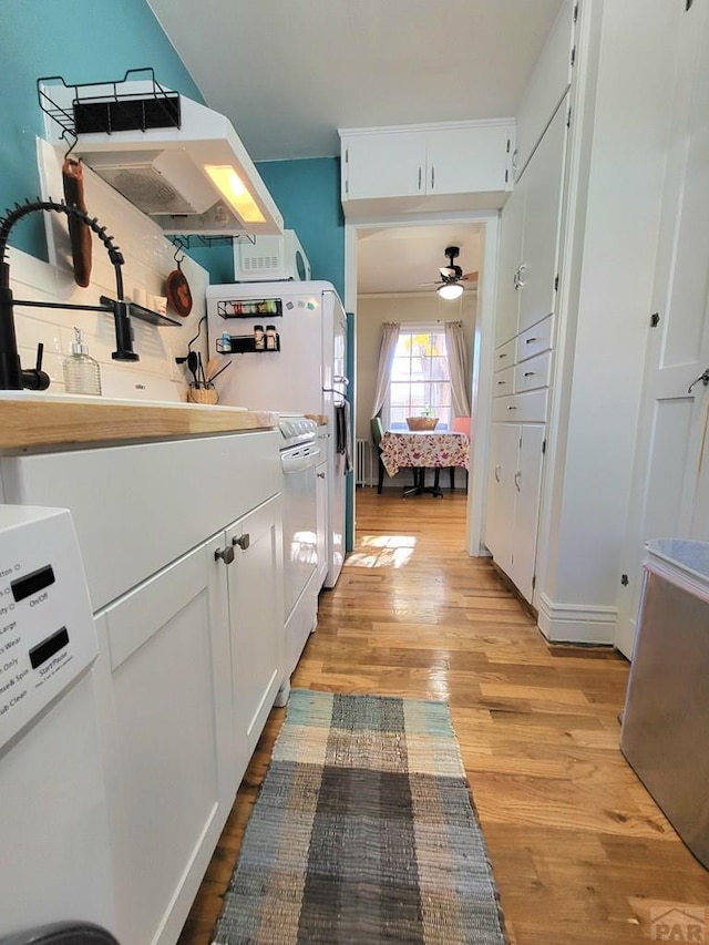 kitchen featuring white microwave, decorative backsplash, light wood-style flooring, white cabinetry, and a ceiling fan