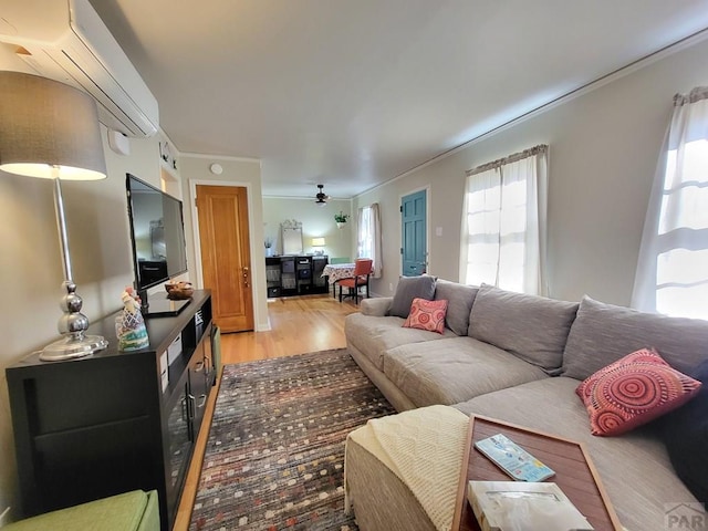 living area with ceiling fan, light wood-style floors, and ornamental molding