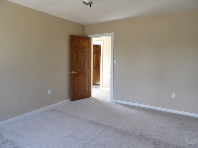 unfurnished room with light colored carpet and baseboards