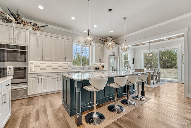 kitchen featuring a kitchen island, appliances with stainless steel finishes, light wood-style floors, a warming drawer, and backsplash