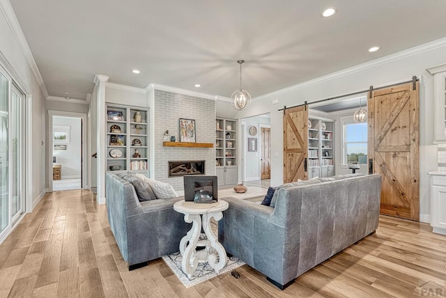 living room featuring baseboards, a barn door, built in shelves, and light wood finished floors