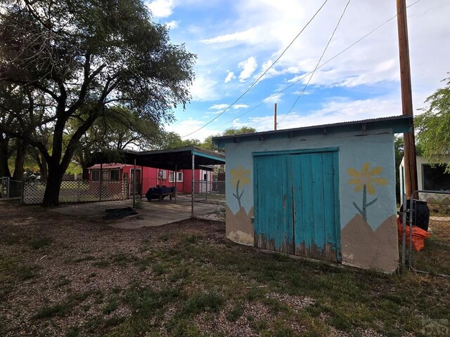 rear view of house with fence, an outbuilding, and stucco siding