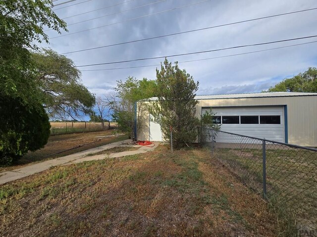 exterior space featuring a yard, fence, and a detached garage