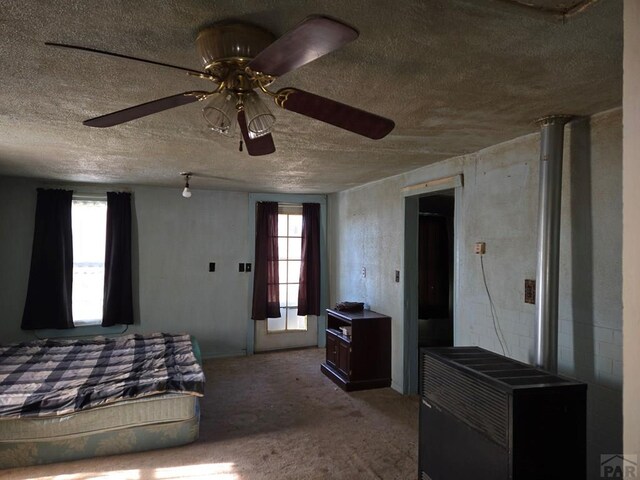 bedroom featuring carpet floors, multiple windows, ceiling fan, and a textured ceiling