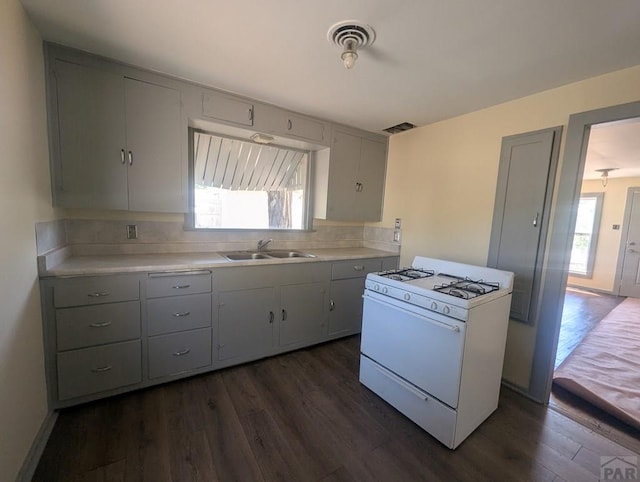 422 Grove Ave, Las Animas, CO 81054 - kitchen with white range with gas cooktop, dark wood-type flooring, light countertops, and tasteful backsplash