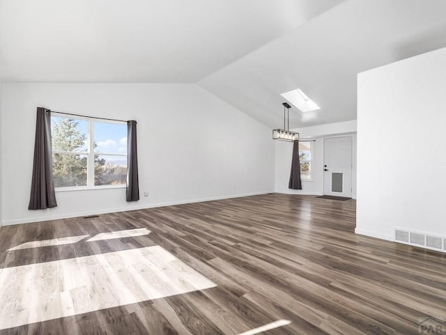 unfurnished living room with vaulted ceiling with skylight, wood finished floors, visible vents, baseboards, and an inviting chandelier