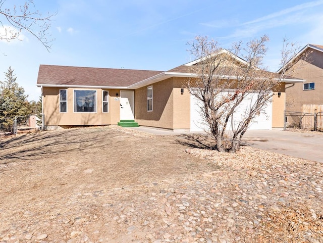 ranch-style house featuring entry steps, driveway, an attached garage, fence, and stucco siding