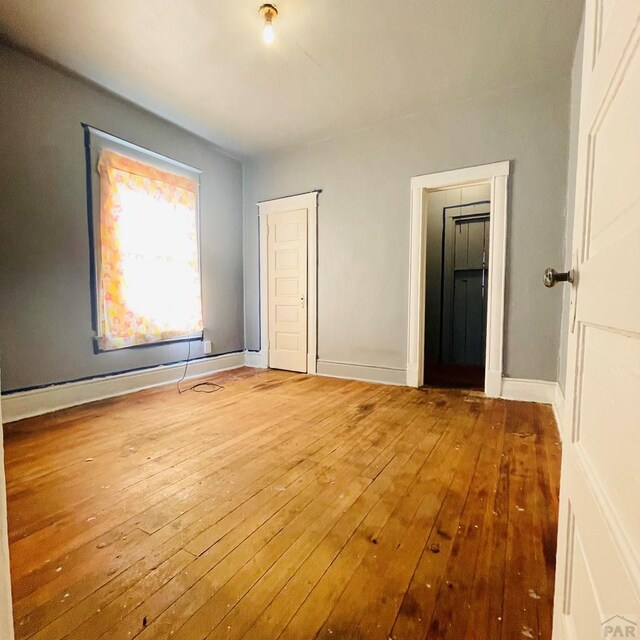 711 E 6th St, Pueblo, CO 81001 - unfurnished bedroom featuring baseboards, baseboard heating, and hardwood / wood-style flooring