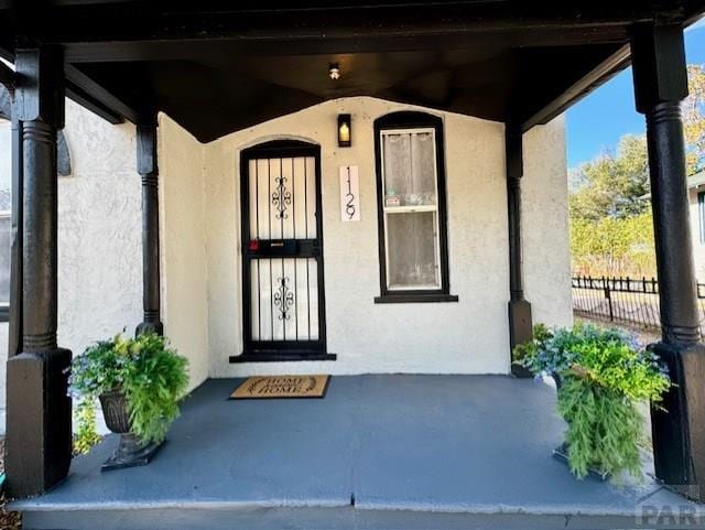 property entrance with fence and stucco siding