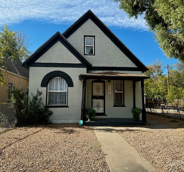 view of front facade featuring a porch, fence, and stucco siding