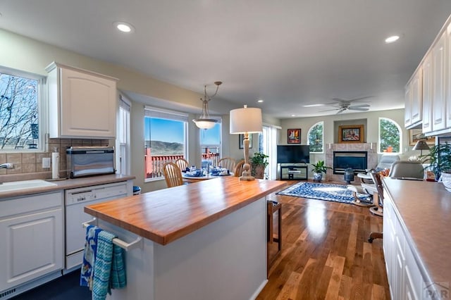 kitchen featuring open floor plan, butcher block countertops, decorative light fixtures, and white cabinets