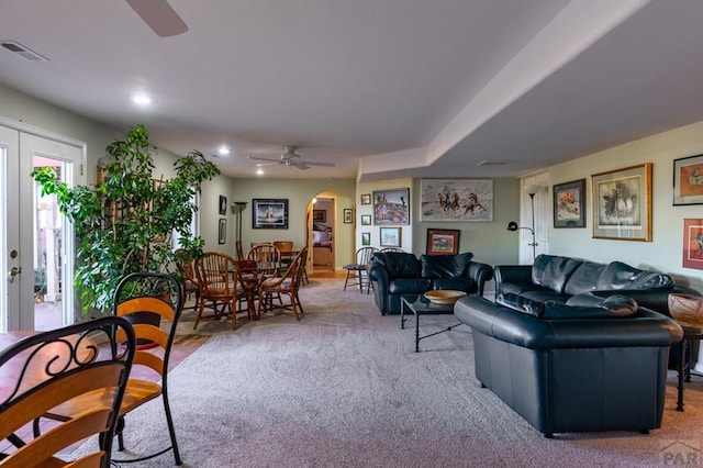 living area featuring arched walkways, recessed lighting, light colored carpet, visible vents, and a ceiling fan