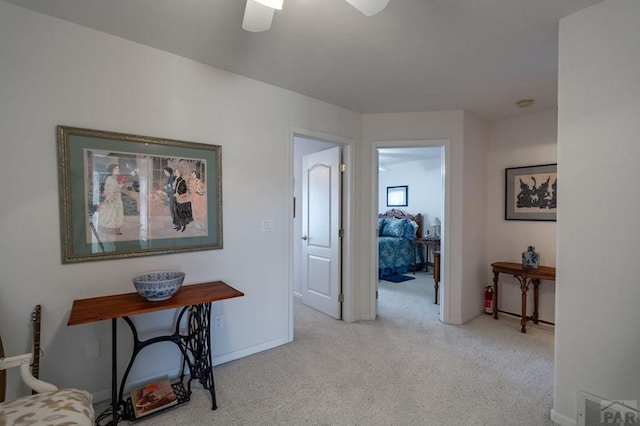 hall featuring light colored carpet, visible vents, and baseboards