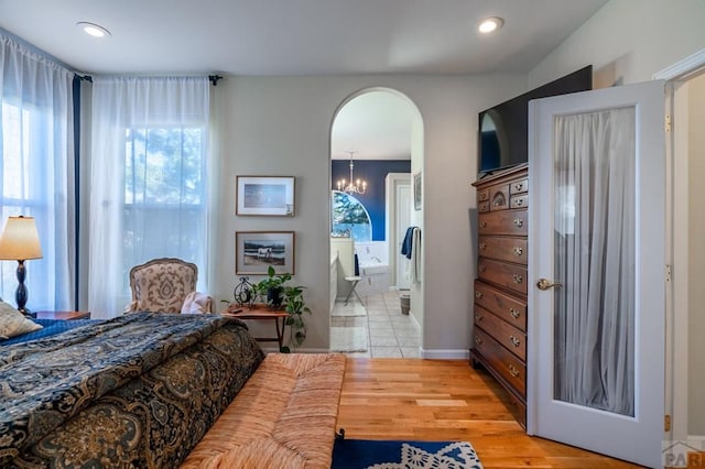 bedroom featuring light wood-type flooring, arched walkways, multiple windows, and recessed lighting