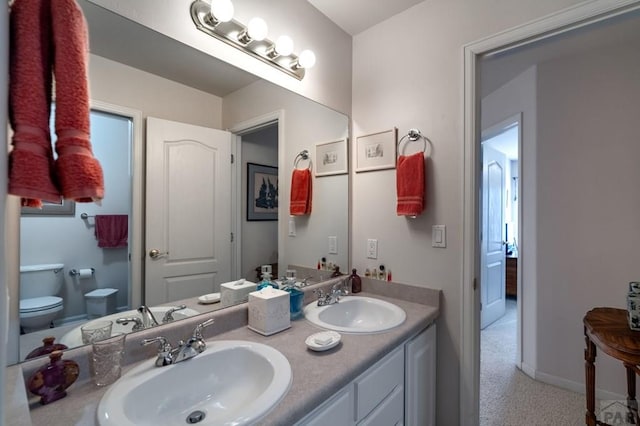 full bath featuring baseboards, a sink, toilet, and double vanity