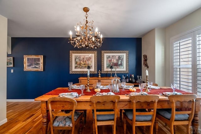 dining space with baseboards, a chandelier, and wood finished floors