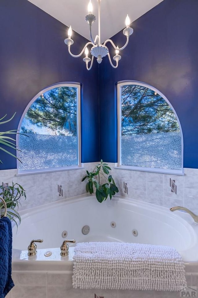 bathroom featuring a chandelier, a healthy amount of sunlight, and a tub with jets