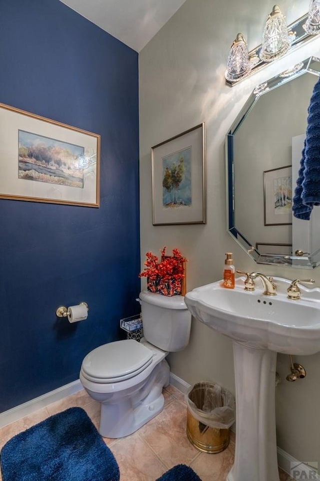 bathroom with toilet, tile patterned flooring, baseboards, and a sink