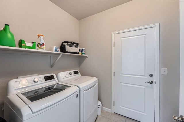 laundry area with light tile patterned floors, laundry area, washing machine and dryer, and baseboards