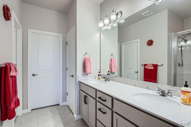 bathroom featuring double vanity, a stall shower, and a sink