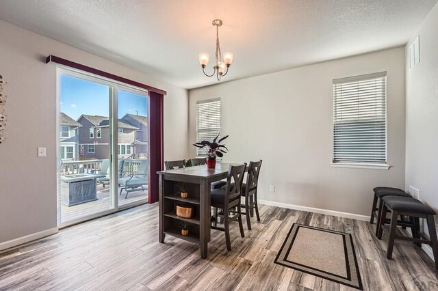 dining area with visible vents, baseboards, wood finished floors, an inviting chandelier, and a textured ceiling