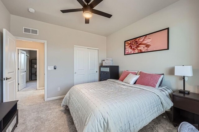 bedroom featuring a closet, light colored carpet, visible vents, a ceiling fan, and baseboards