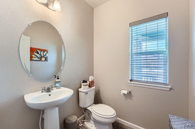 bathroom featuring baseboards, a sink, and toilet