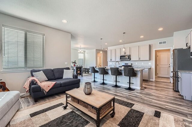 living area with light wood-type flooring, recessed lighting, visible vents, and baseboards