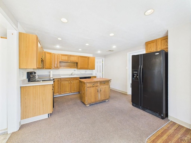 705 Euclid Ave, Pueblo, CO 81004 - kitchen with black fridge, a kitchen island, recessed lighting, light countertops, and light colored carpet
