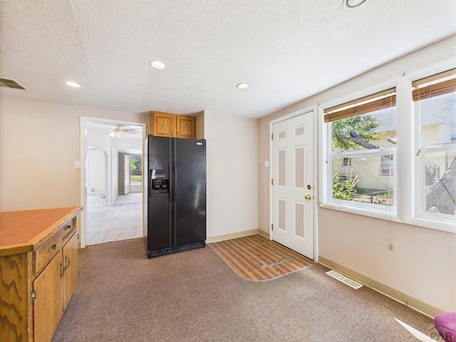 705 Euclid Ave, Pueblo, CO 81004 - kitchen with black fridge with ice dispenser, tile countertops, carpet floors, brown cabinets, and recessed lighting