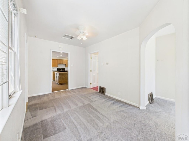 705 Euclid Ave, Pueblo, CO 81004 - unfurnished living room with arched walkways, light colored carpet, and ceiling fan