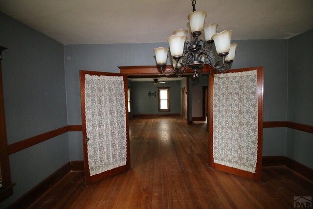 interior space with a chandelier, dark wood-type flooring, and baseboards