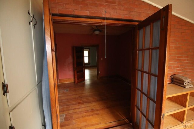 hallway with brick wall and wood finished floors