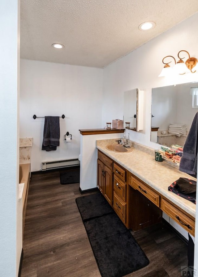 11210 Eggar Dr, Peyton, CO 80831 - full bathroom with vanity, a textured ceiling, a baseboard heating unit, and wood finished floors