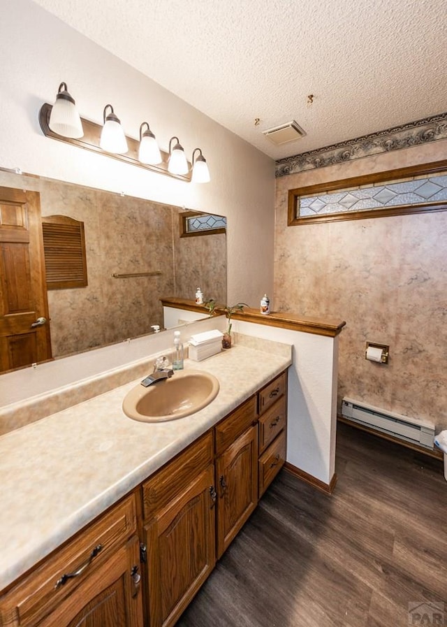 11210 Eggar Dr, Peyton, CO 80831 - bathroom featuring a textured ceiling, wood finished floors, vanity, and a baseboard radiator