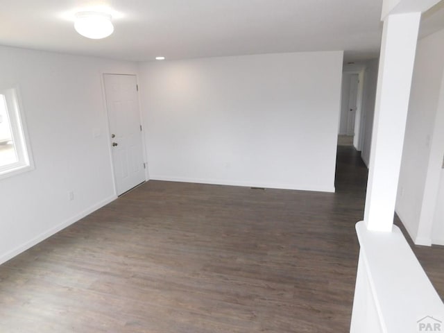 unfurnished room with baseboards and dark wood-style flooring