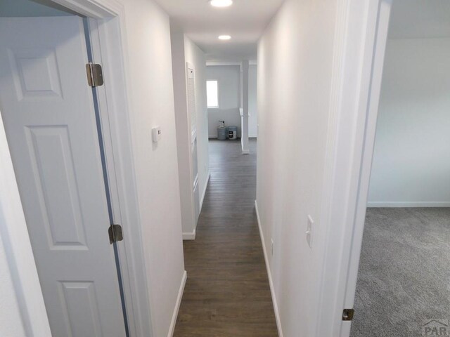 corridor with dark wood-type flooring and baseboards